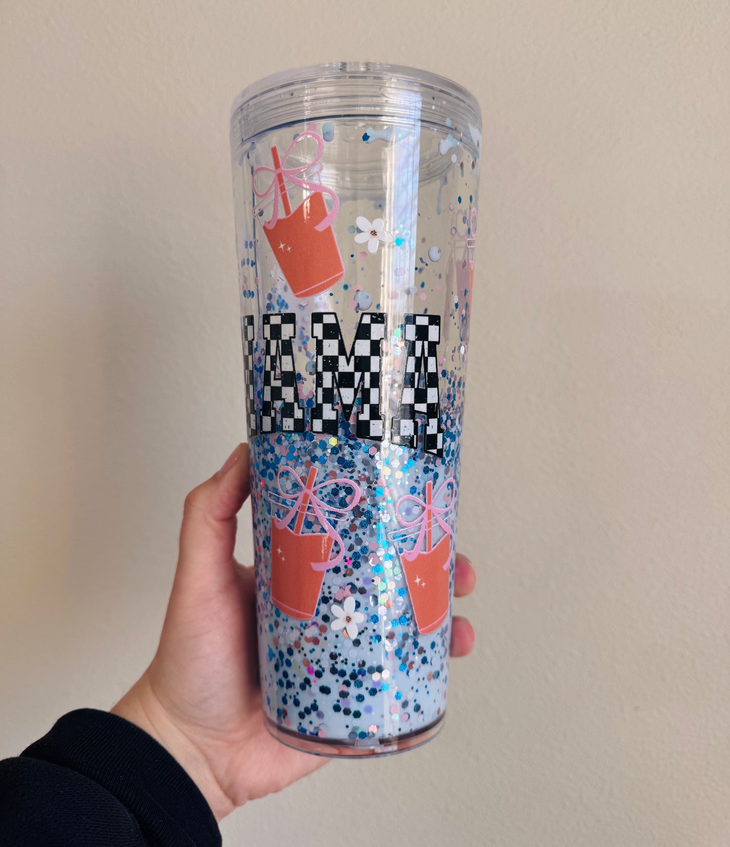 Tumbler with colorful design and text held by a hand against a plain background