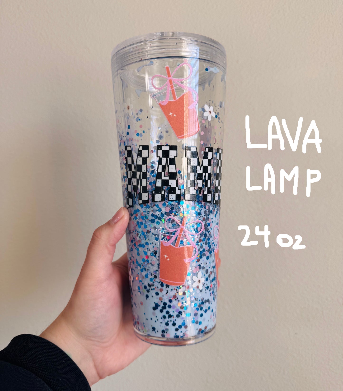 Clear tumbler with colorful confetti design held by a hand against a plain background
